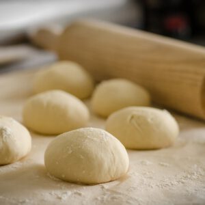 Foto van deegroller en meerdere deegbollen voor pizza
