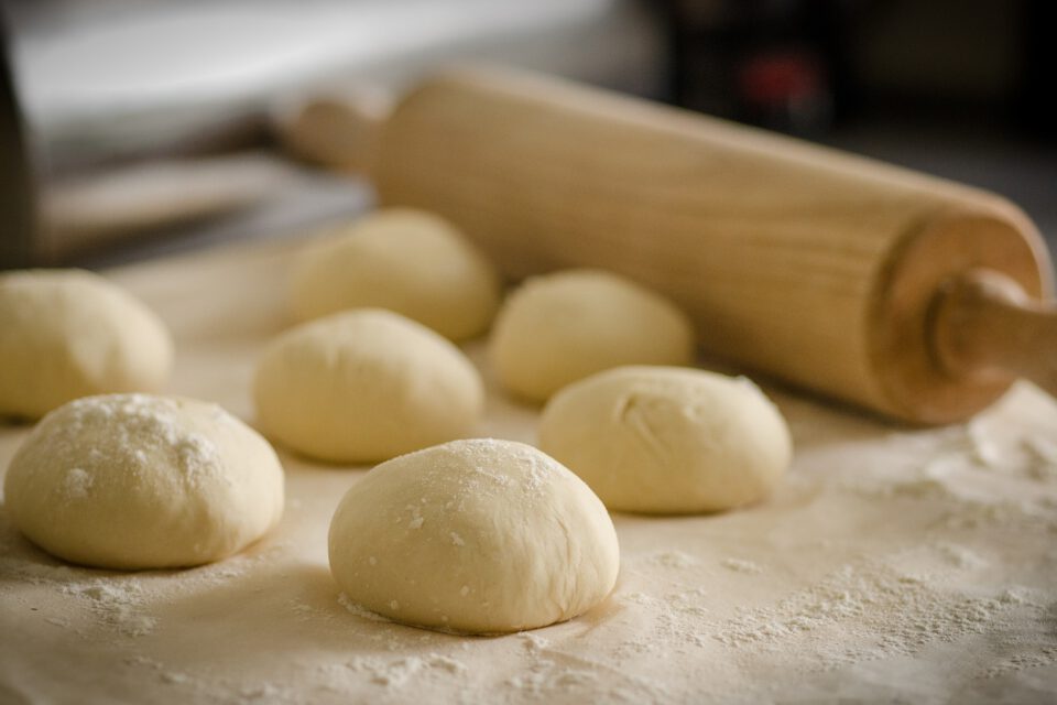 Foto van deegroller en meerdere deegbollen voor pizza